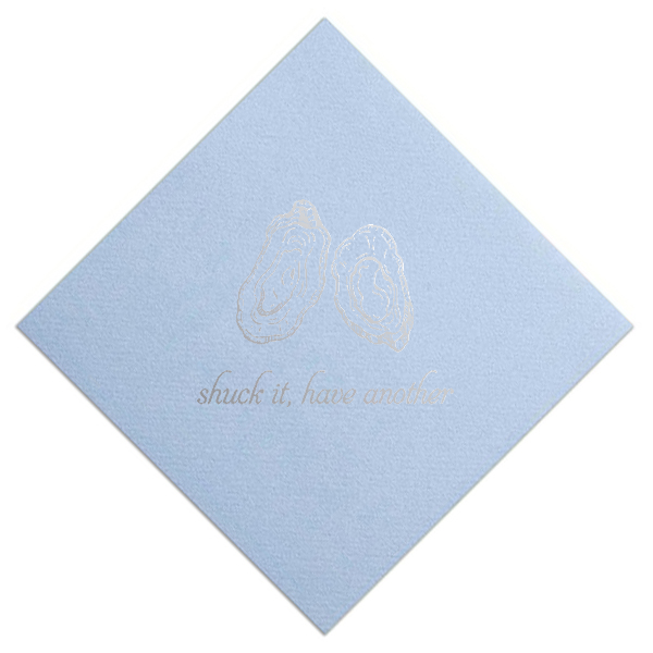 Powder blue linen-like cocktail napkin featuring two delicate oyster shell illustrations in shiny silver foil with elegant script lettering reading “shuck it, have another.”