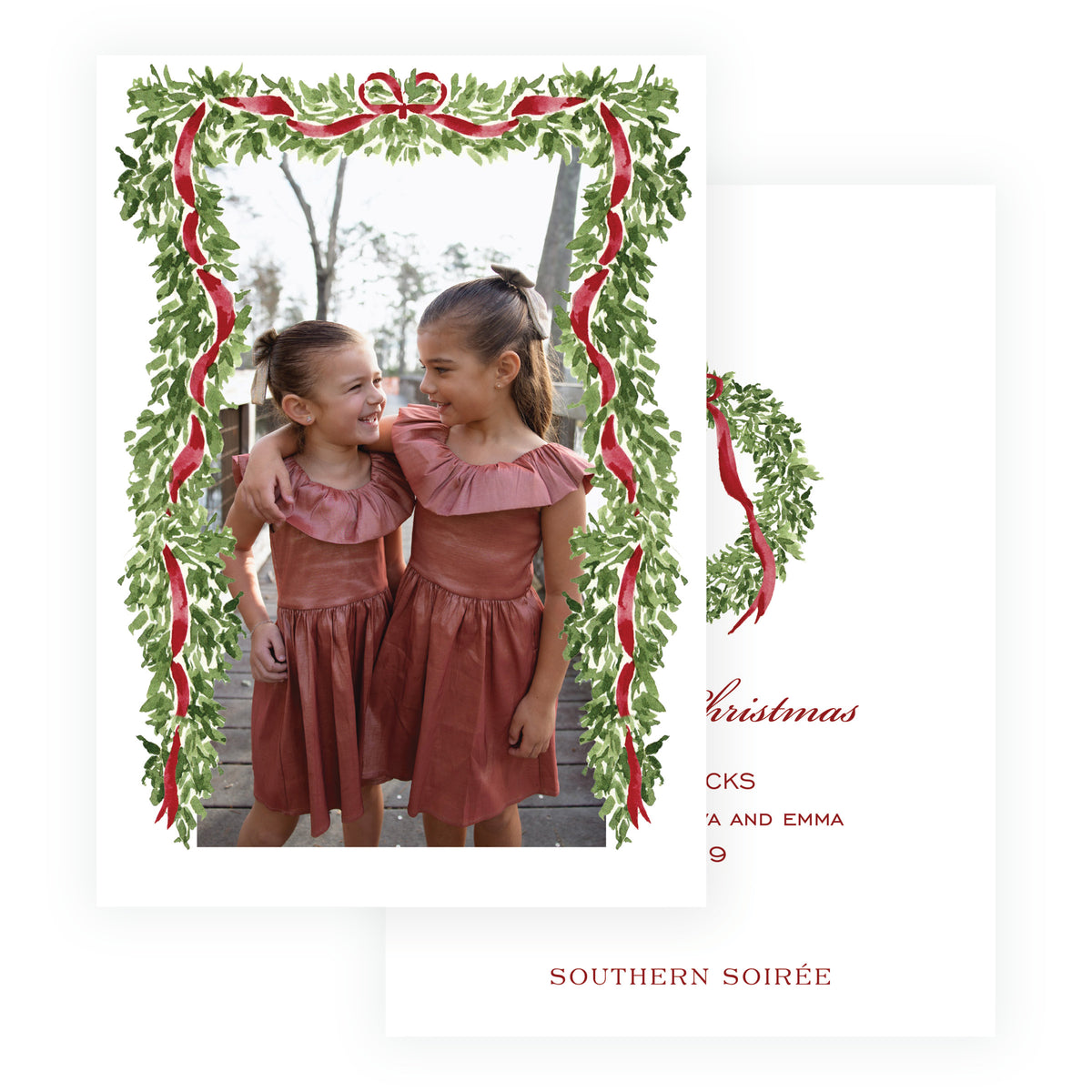Personalized family Christmas photo card surrounded by greenery and burgundy ribbon