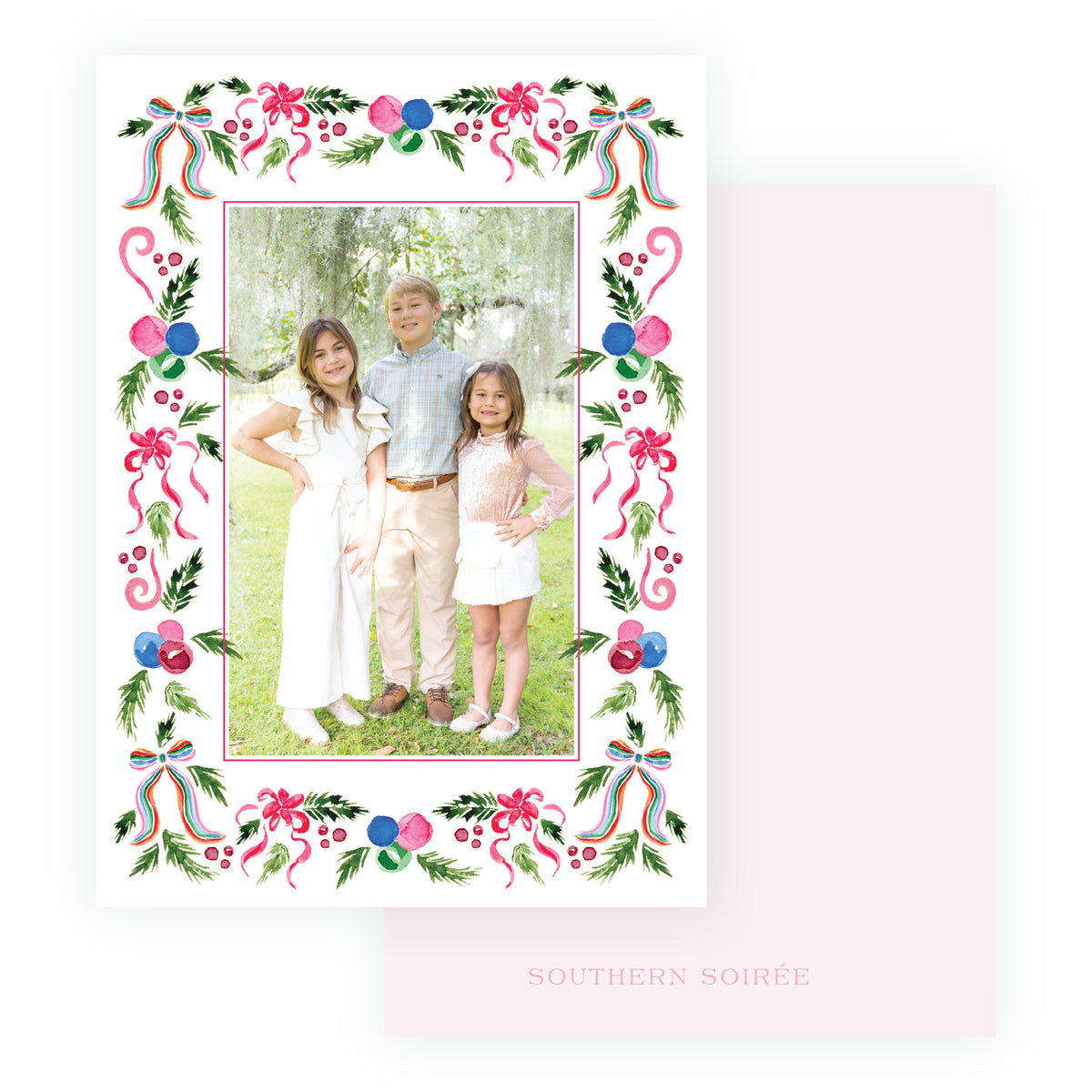 A square holiday photo card with a white border decorated with pink bows, green leaves, red berries, and blue ornaments, featuring a central photo.