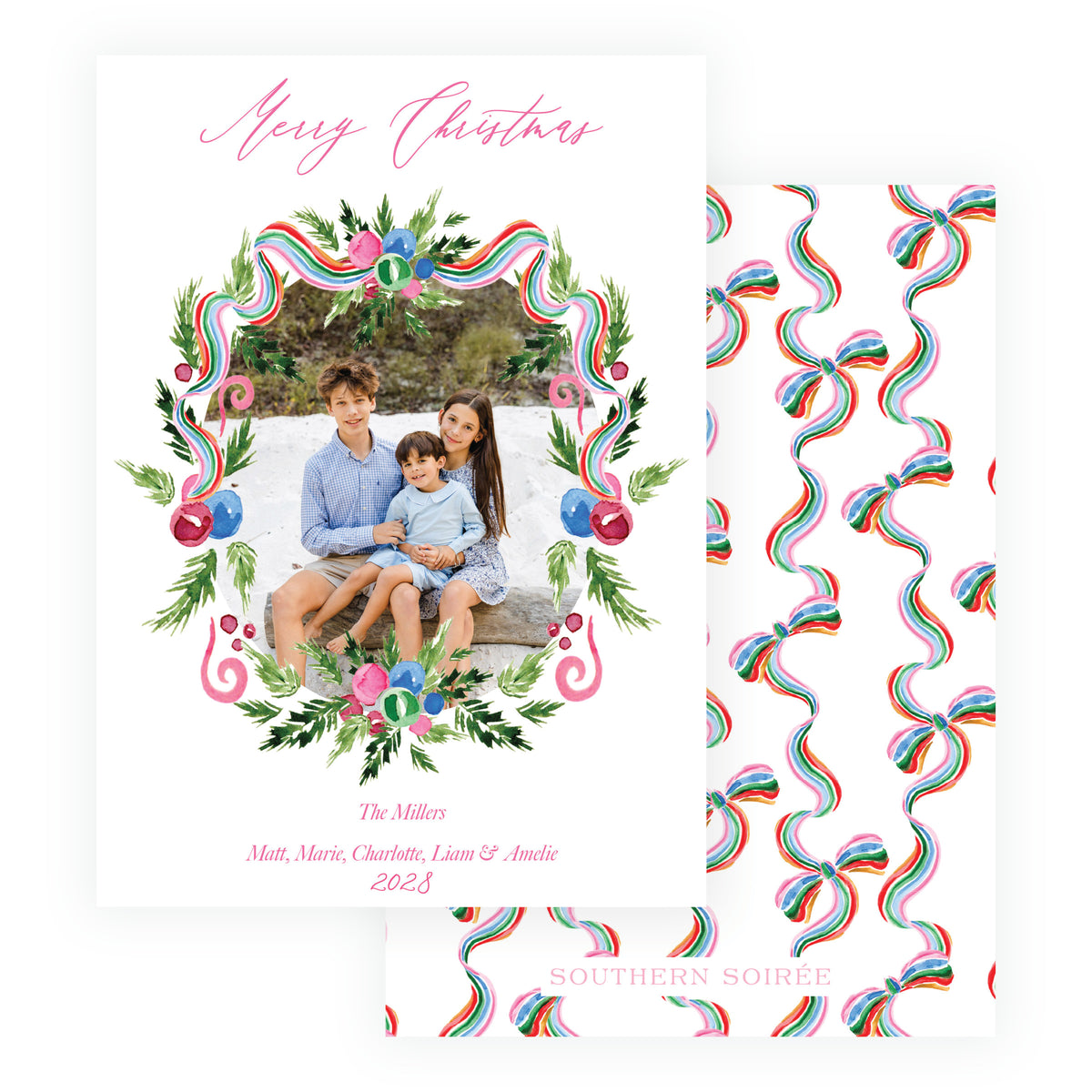 A Christmas greeting card. The front card is white with pink script text reading 'Merry Christmas' and a colorful watercolor wreath frame around a family photo.