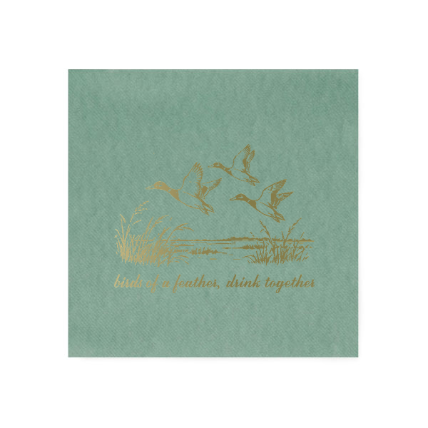 Eucalyptus green linen-like cocktail napkin featuring three vintage-style mallard ducks flying over marsh grass, printed in brushed gold foil with the phrase “birds of a feather, drink together.”